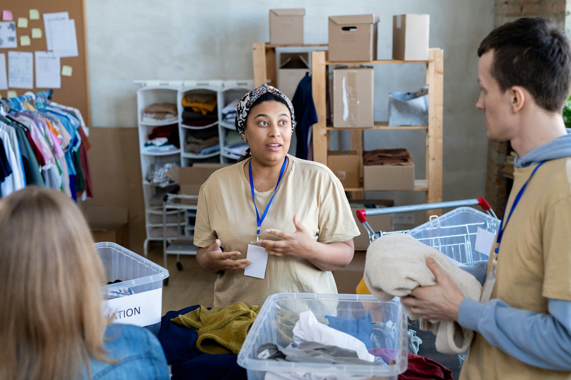 The image shows a charity volunteer working at a donation center alongside other volunteers
