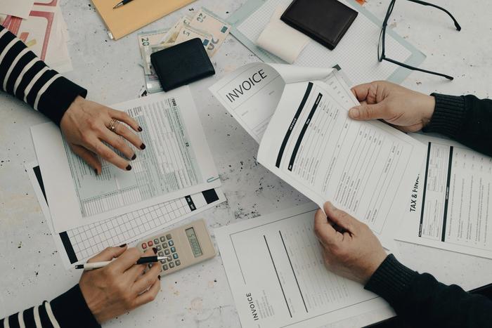 a man and a woman are sitting at a table with papers and a calculator.