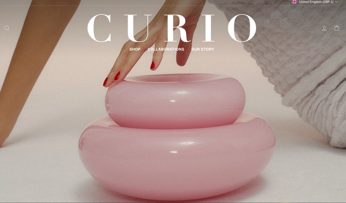 a woman 's hand is reaching for a pink object on the curio website