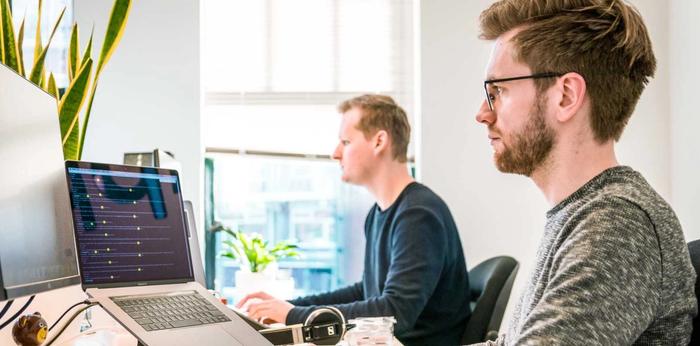 Image shows two men working at desks.