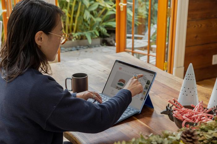 a woman is sitting at a table using a laptop computer .