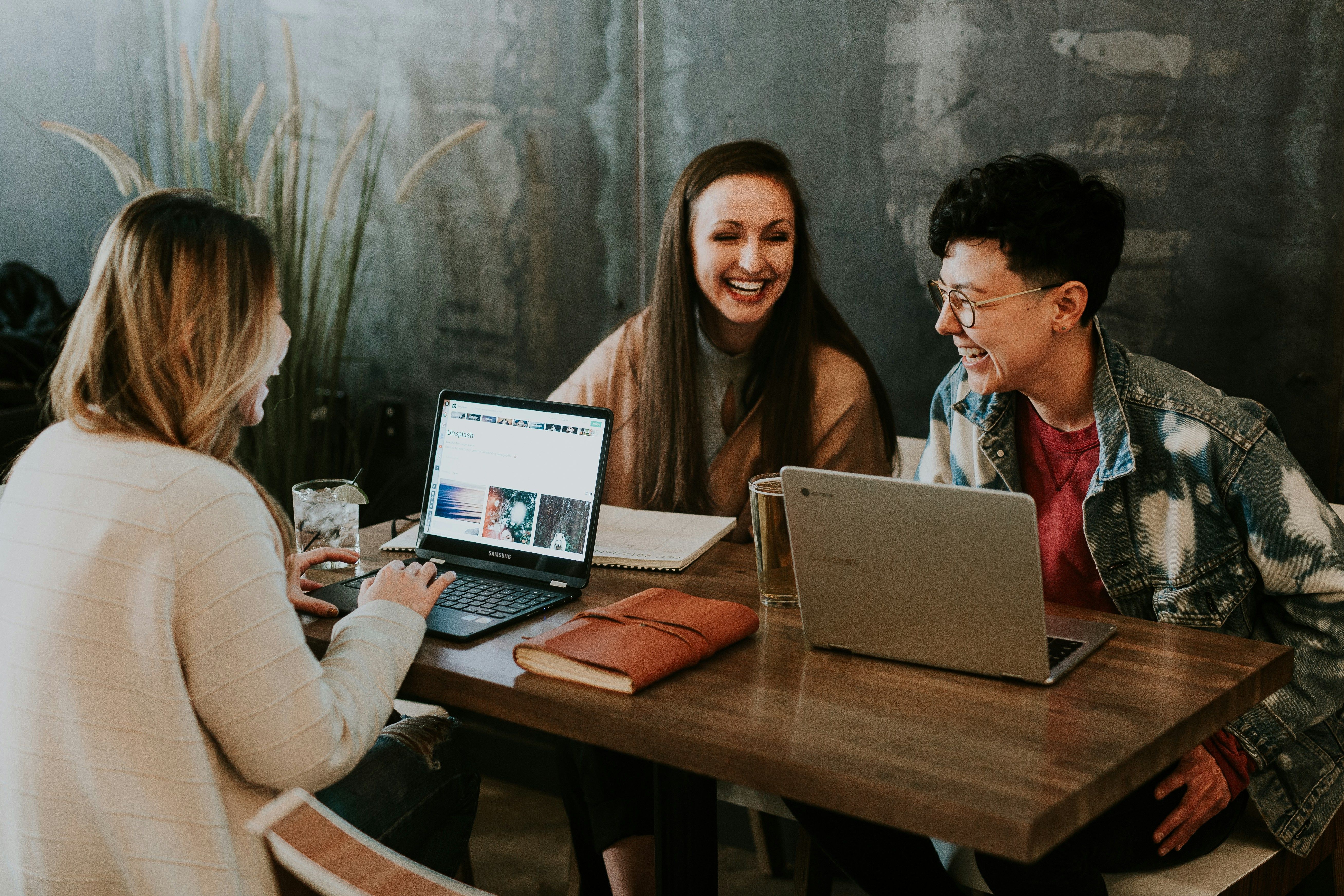 three office workers laughing while sat round a table