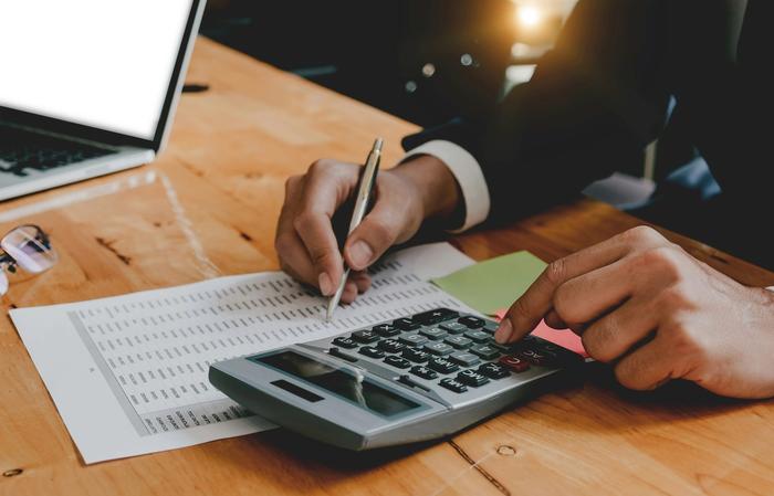a person is using a calculator and writing on a piece of paper .