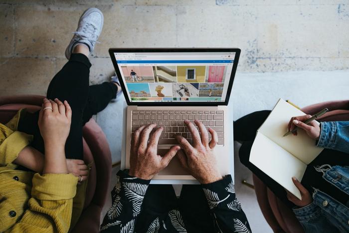 a group of people are sitting in chairs using a laptop computer .