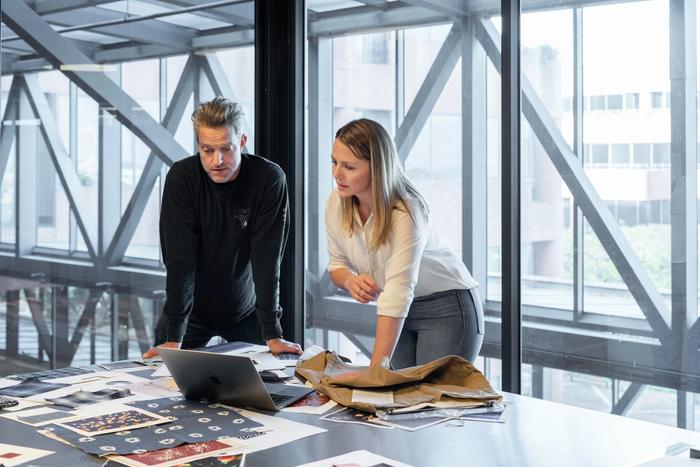 a man and a woman are looking at a laptop on a table .