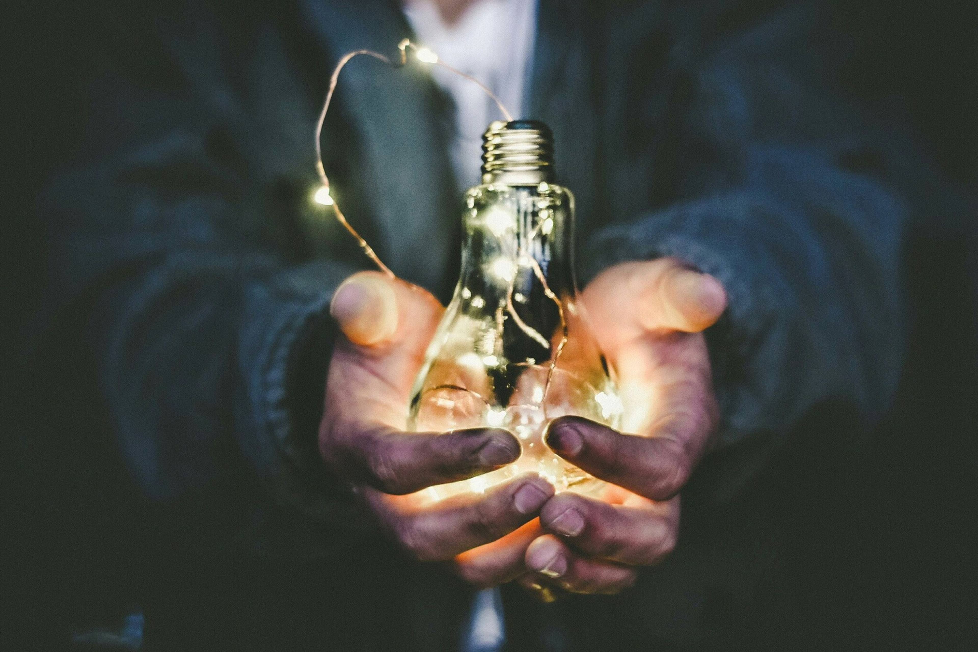 Hands holding a glowing light bulb in the dark Cambridge Radar