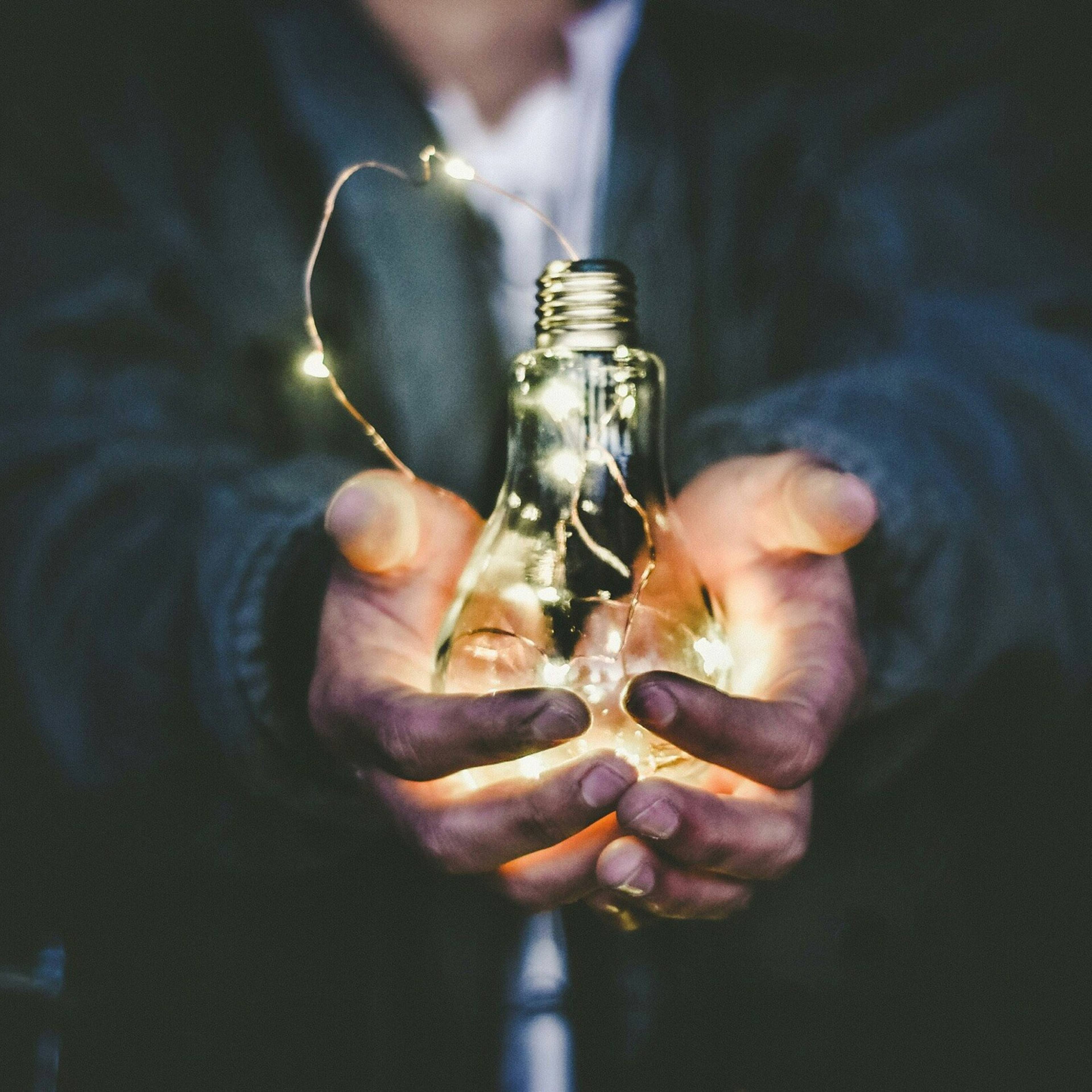 Hands holding a glowing light bulb in the dark Cambridge Radar