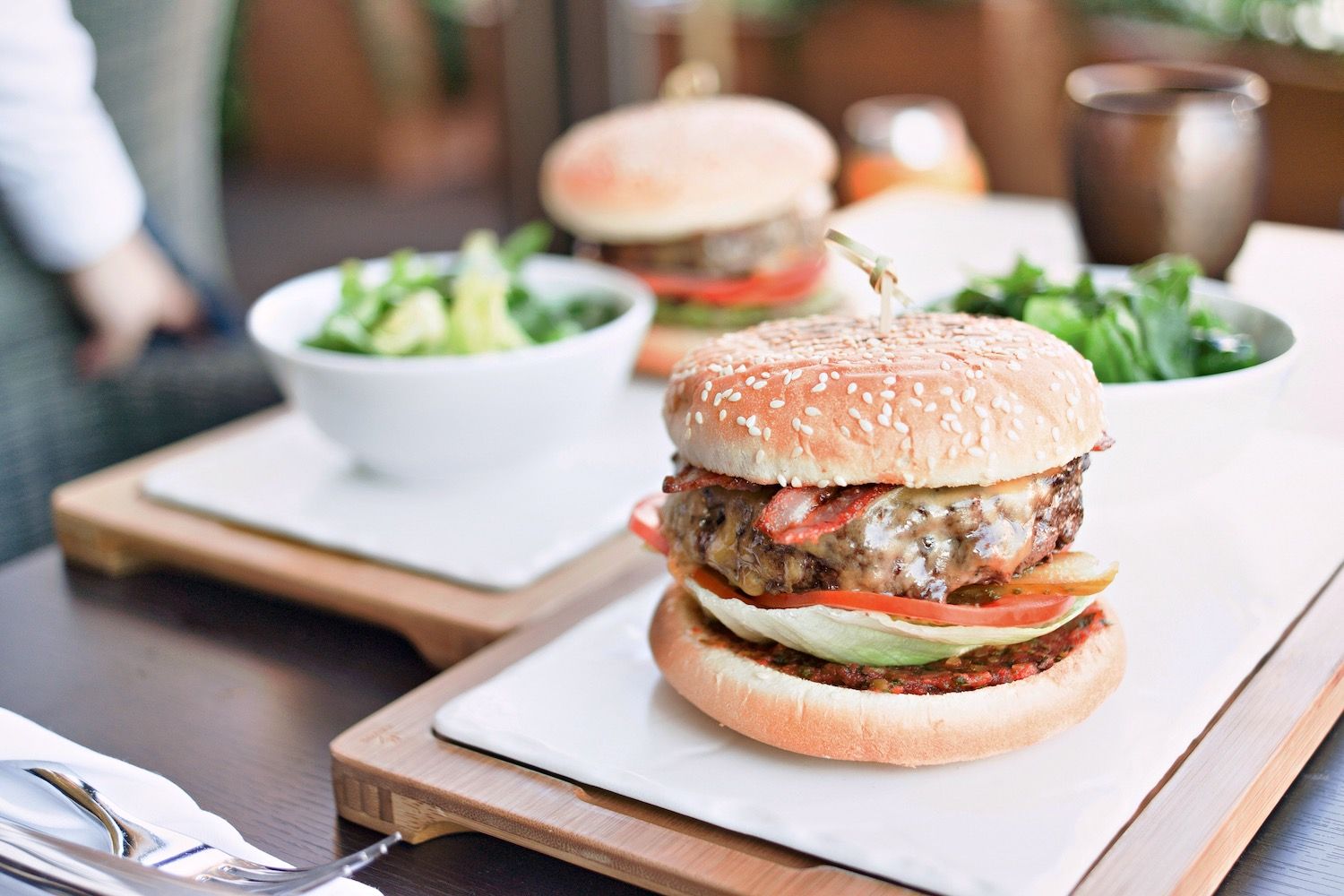 Cheeseburger with lettuce and tomato served alongside a green salad