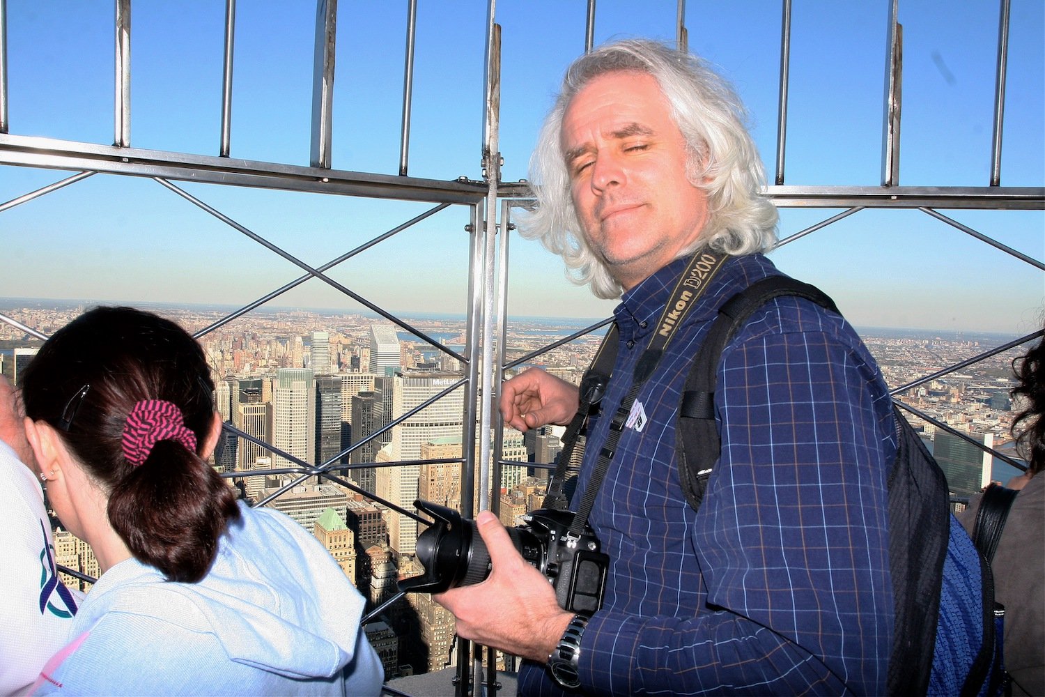 Man holding a camera on an observation deck above a city