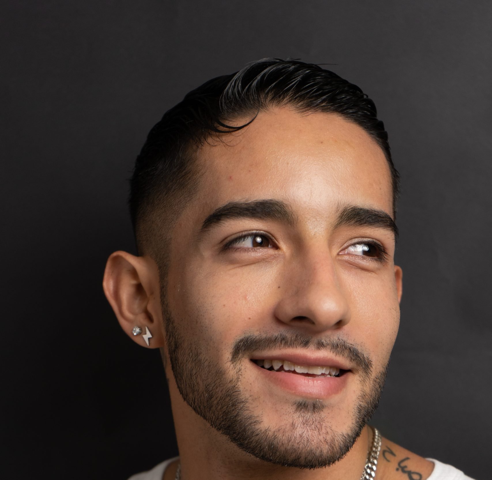 Smiling man with short dark hair and trimmed beard looks upward