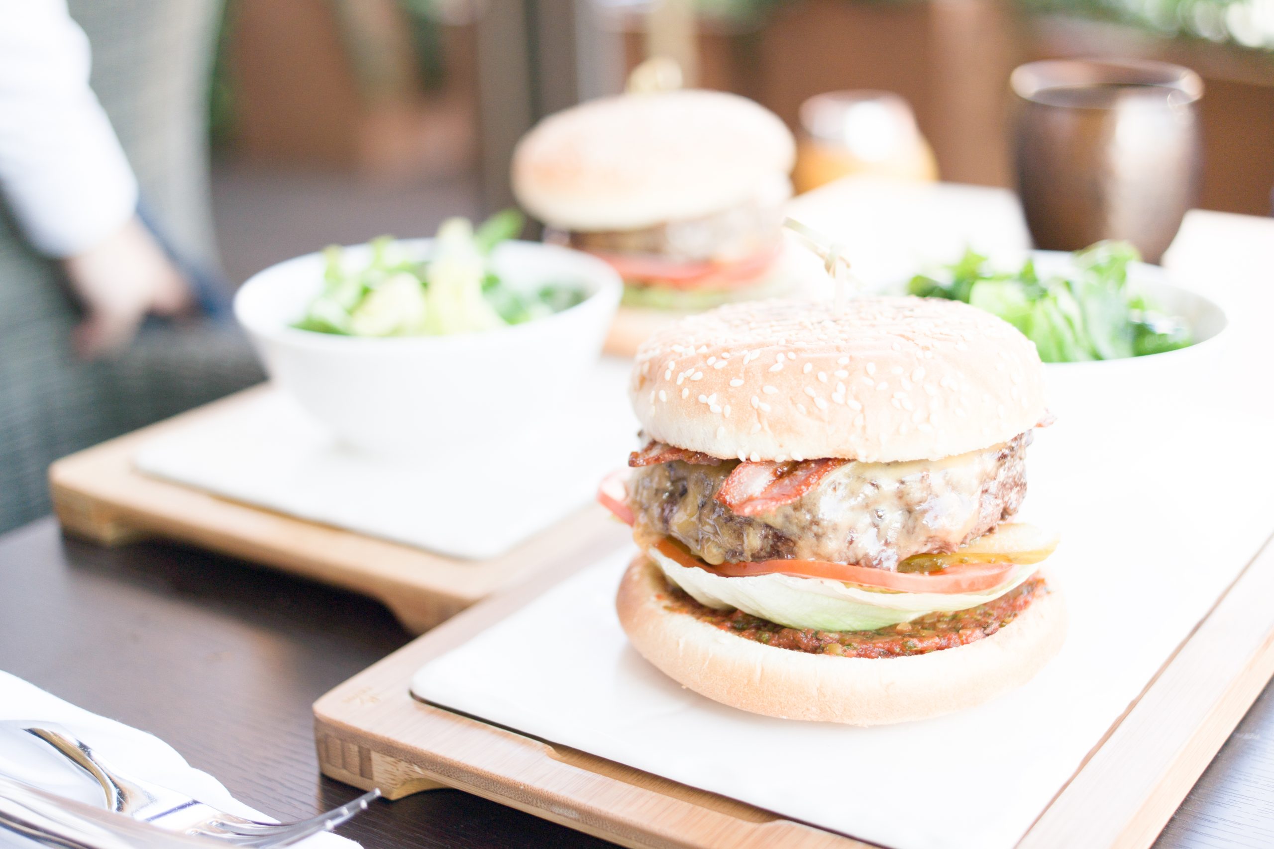 Cheeseburger with lettuce and tomato served alongside a green salad