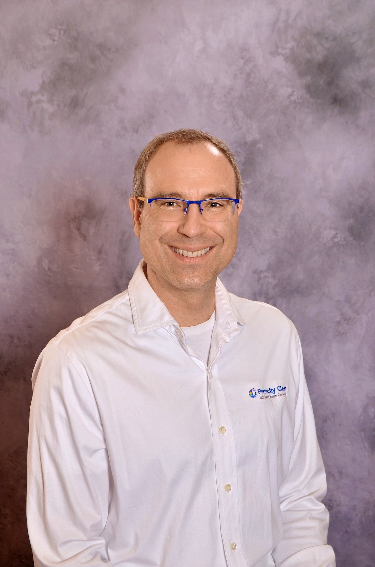 Smiling man wearing glasses and a Perfectly Clear shirt