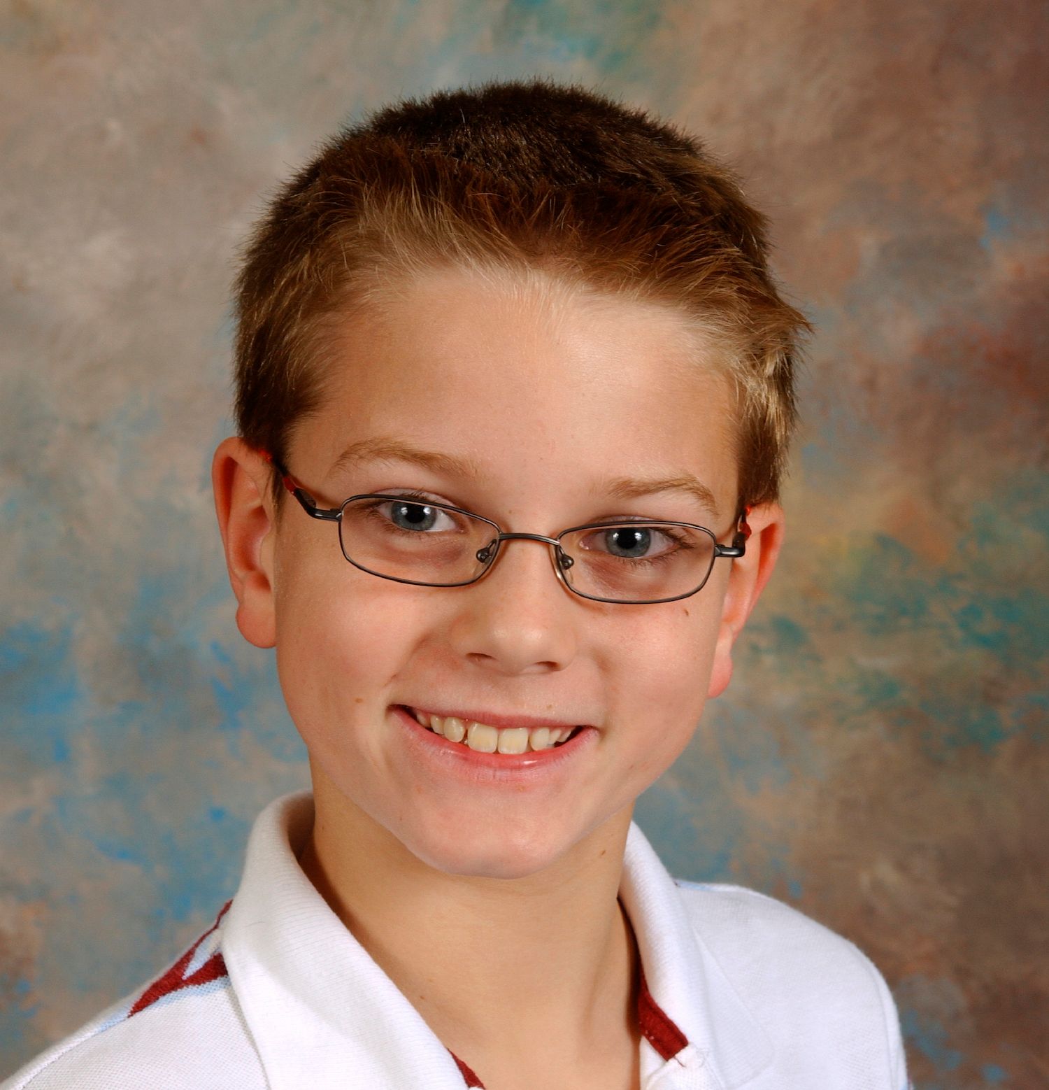 Smiling boy wearing glasses and a white collared shirt