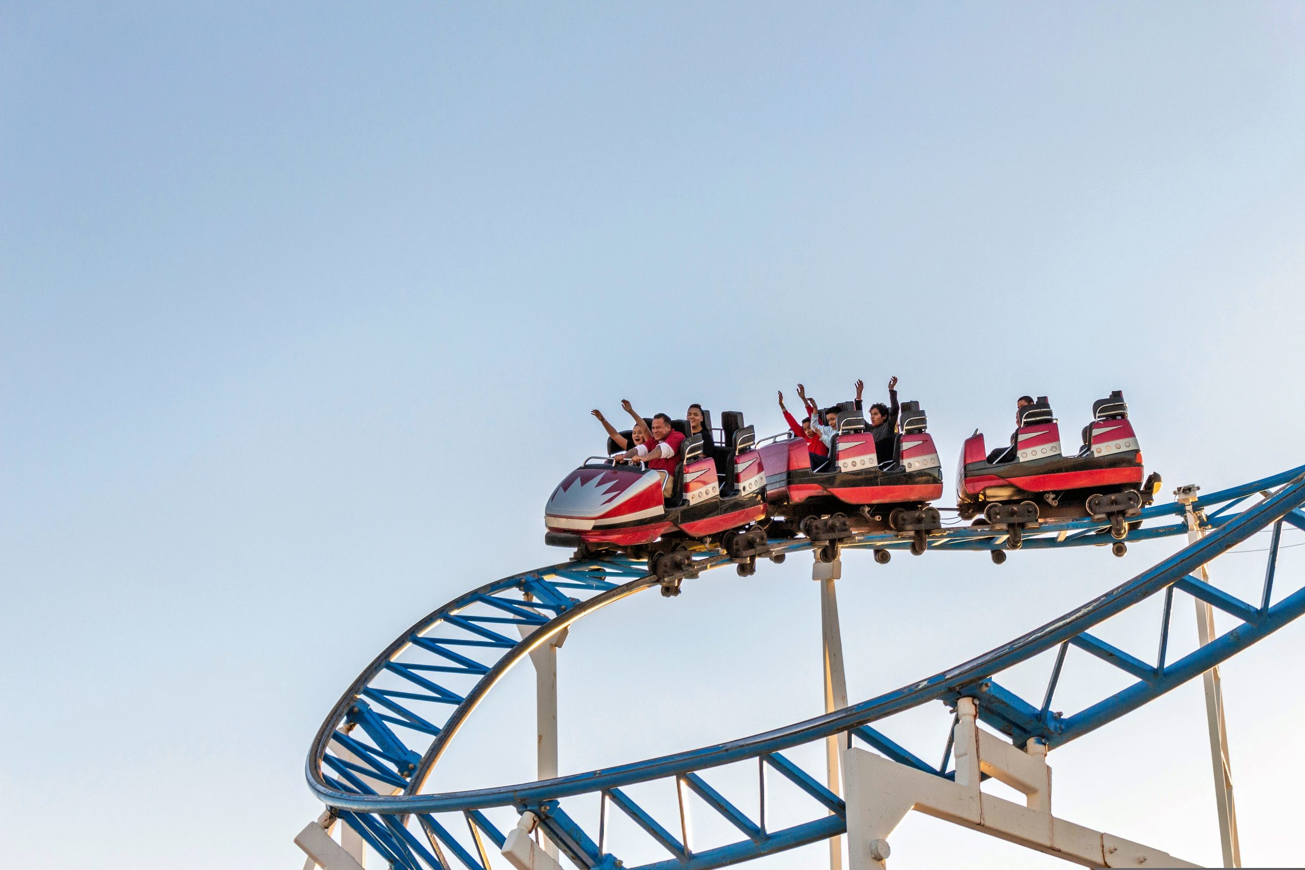 Roller coaster riders raise their arms on a curved track