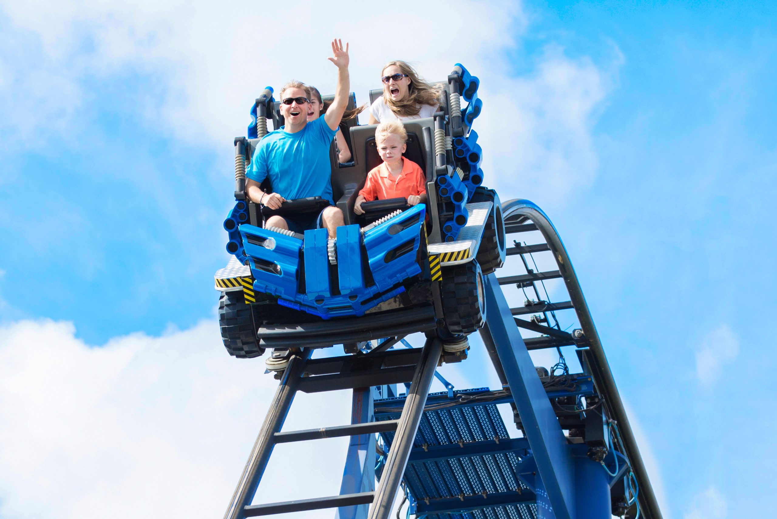 Family rides a roller coaster over the crest of a hill