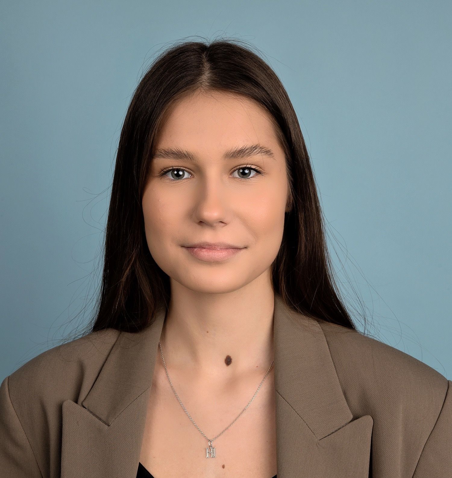 Woman with long dark hair wearing a blazer and necklace
