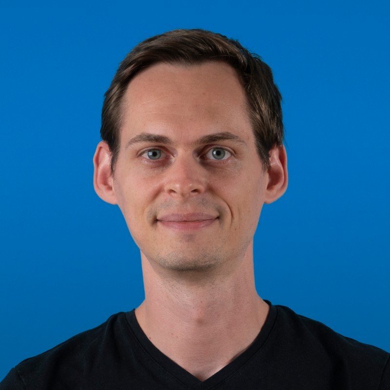 Man smiling slightly against a blue background