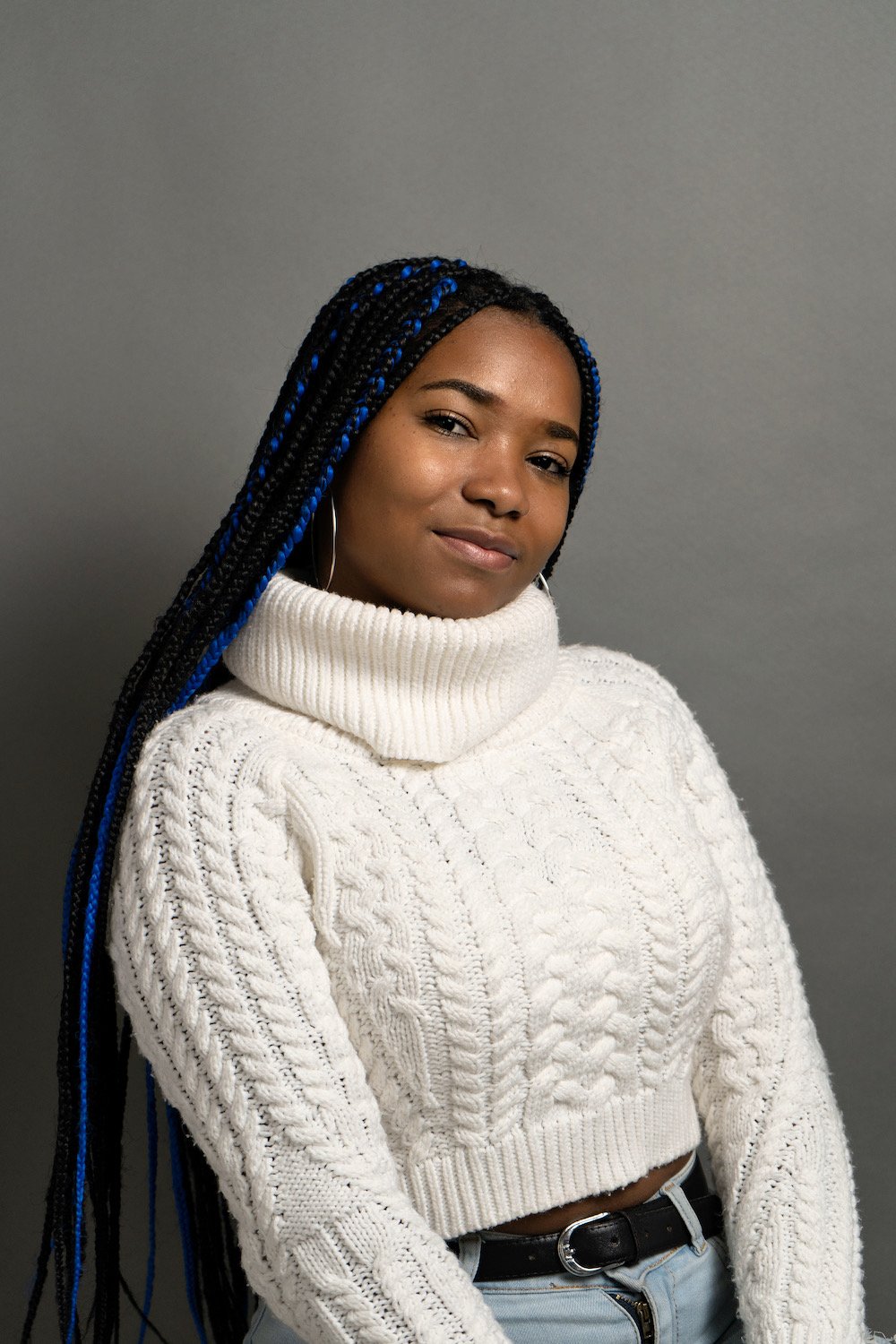 Woman with long braids wearing a white cable-knit turtleneck sweater