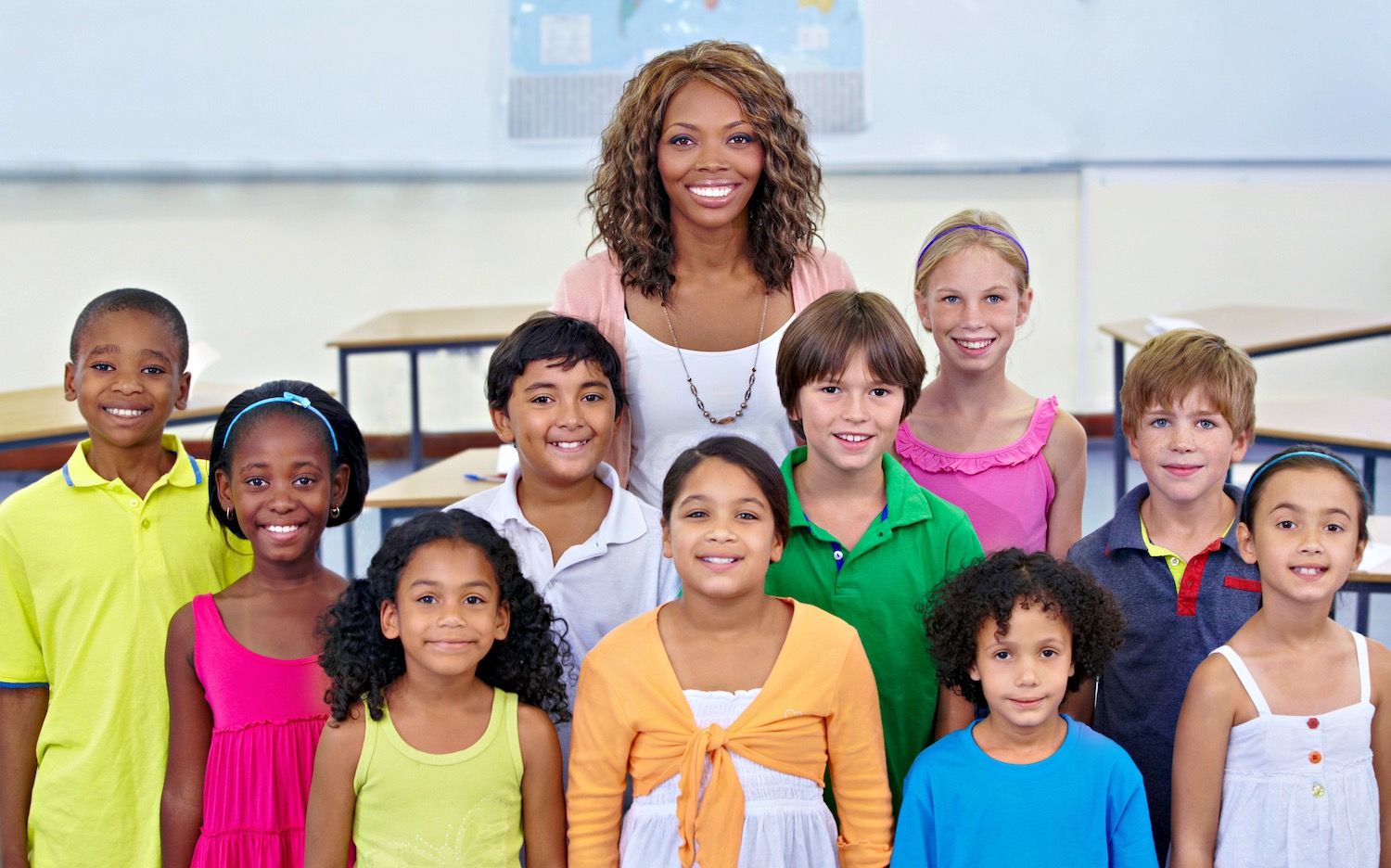 Teacher and diverse group of smiling elementary students in a classroom