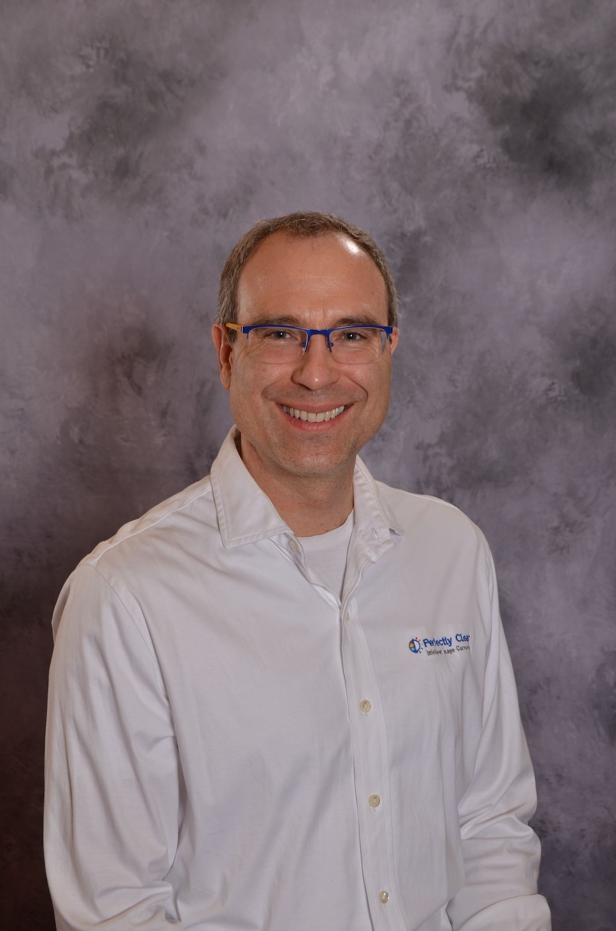 Smiling man wearing glasses and a Perfectly Clear shirt