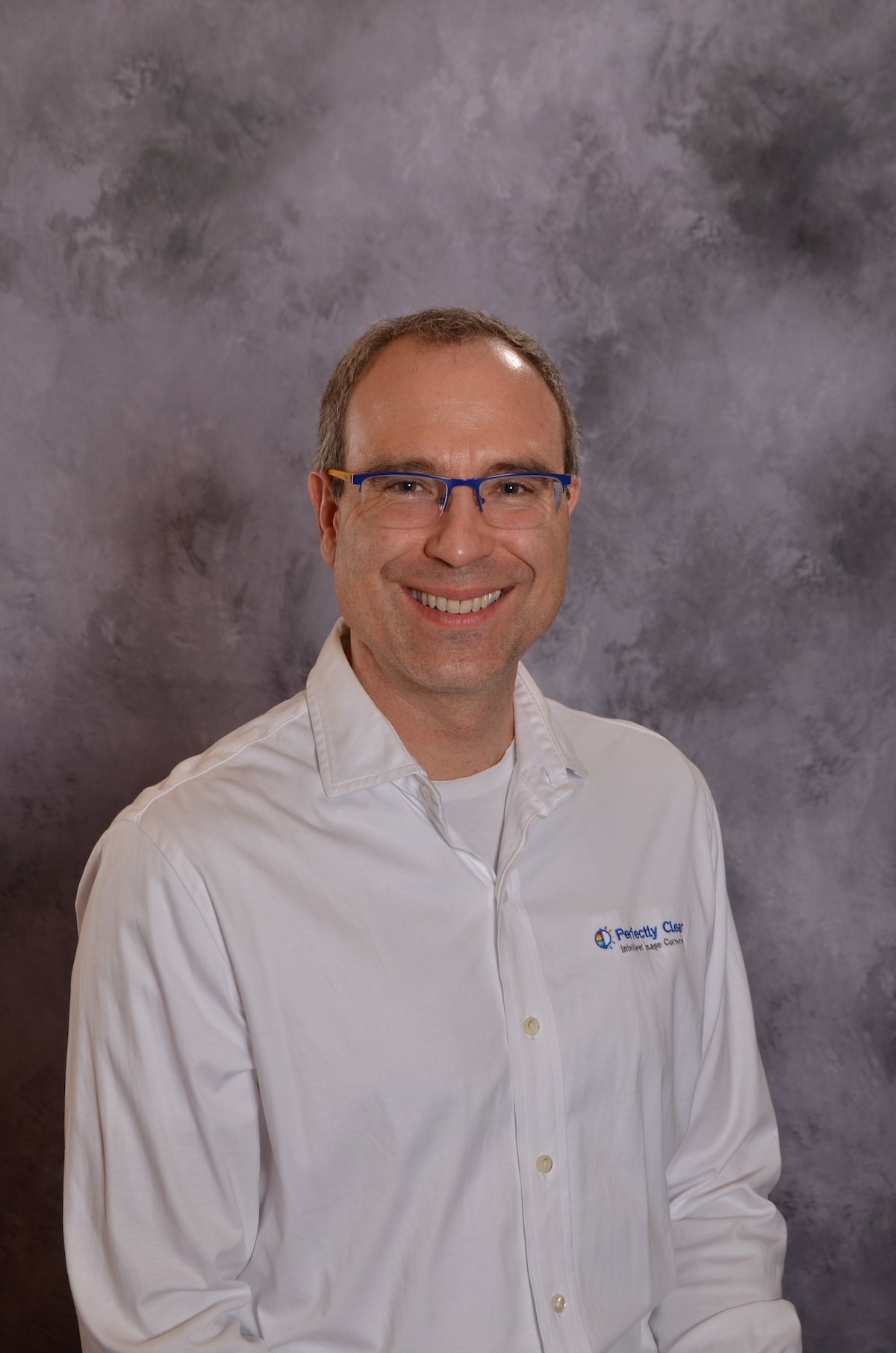 Smiling man wearing glasses and a Perfectly Clear shirt