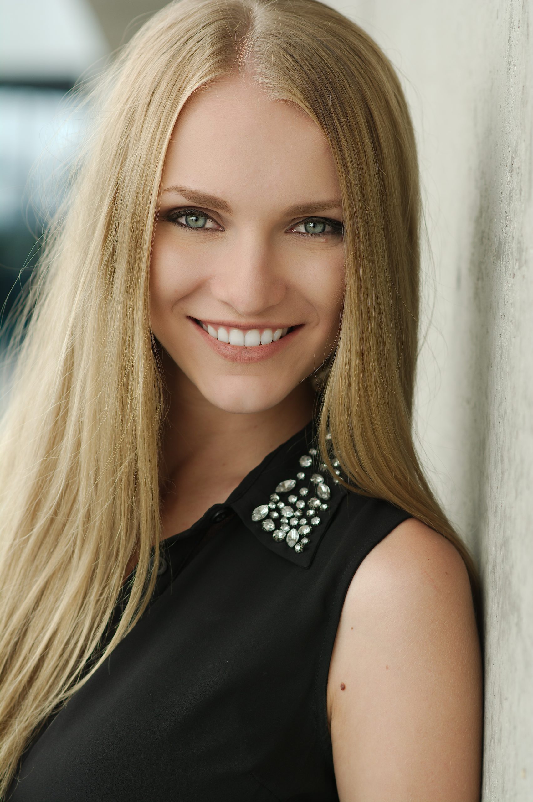 Smiling woman with long blonde hair wearing a black jeweled-collar top
