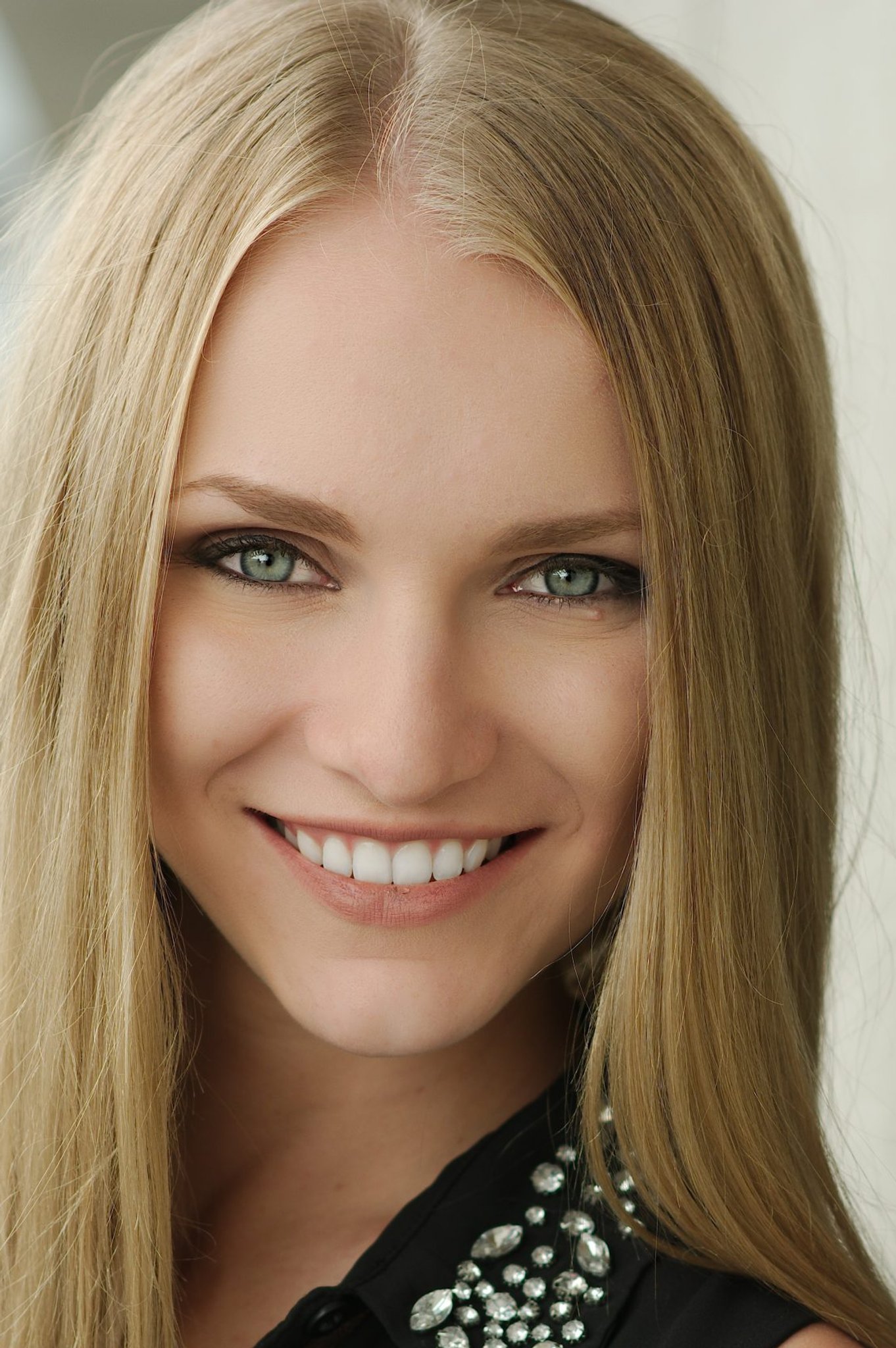 Smiling woman with long blonde hair wearing a black jeweled-collar top