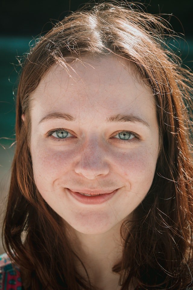 Young woman with long brown hair smiling at the camera
