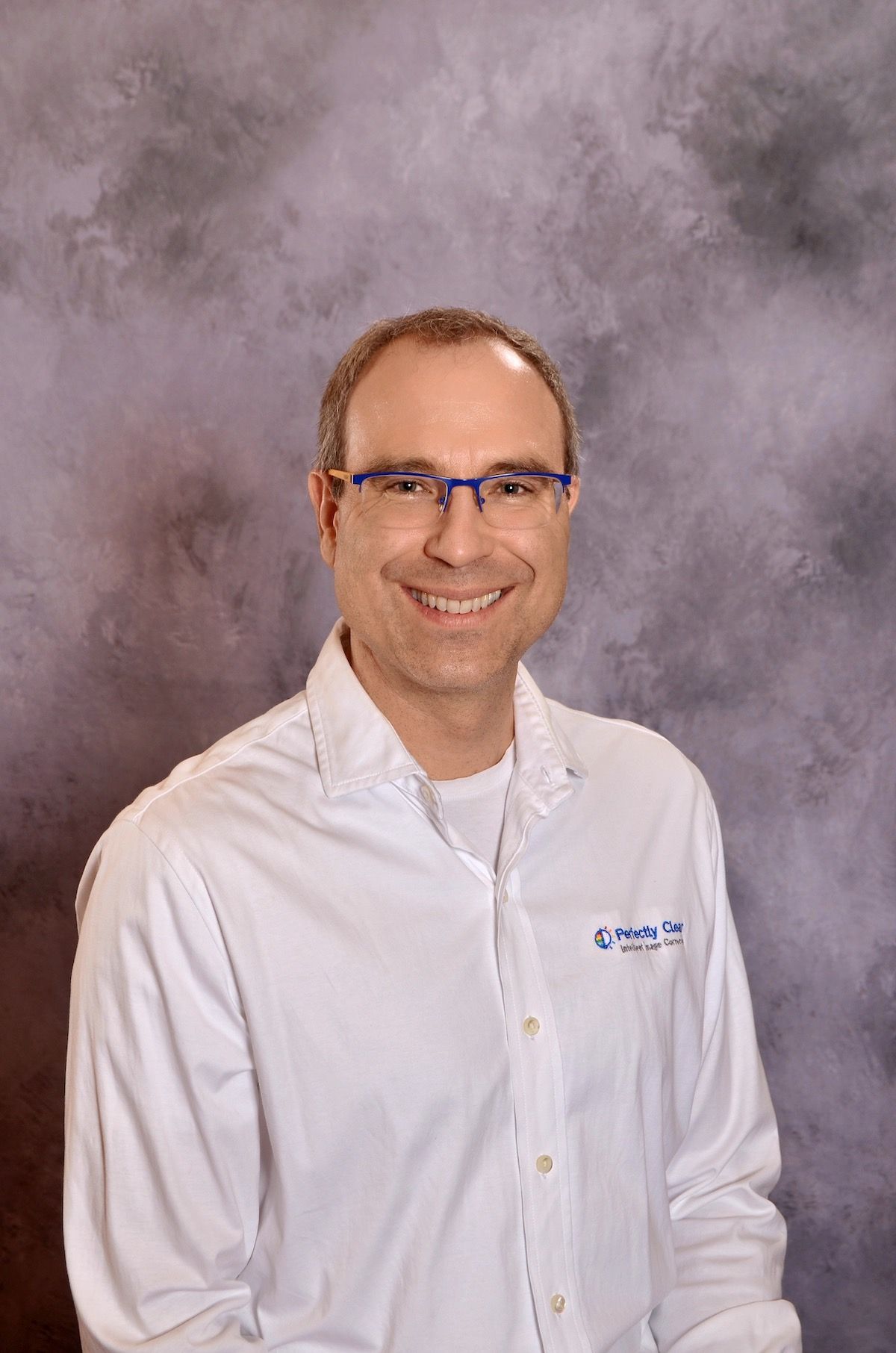 Smiling man wearing glasses and a Perfectly Clear shirt