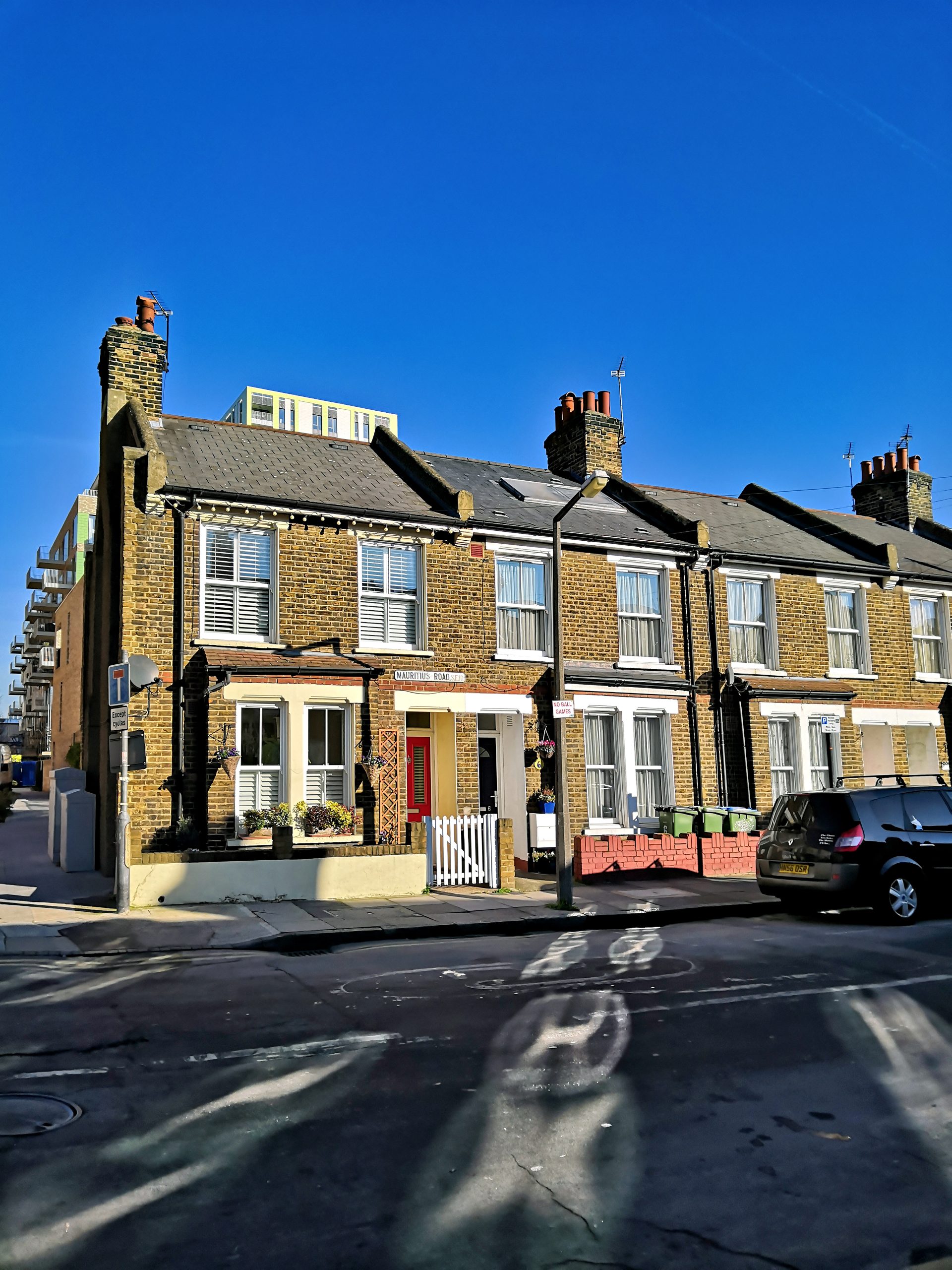 Brick terraced houses line Mauritius Road beside a parked car