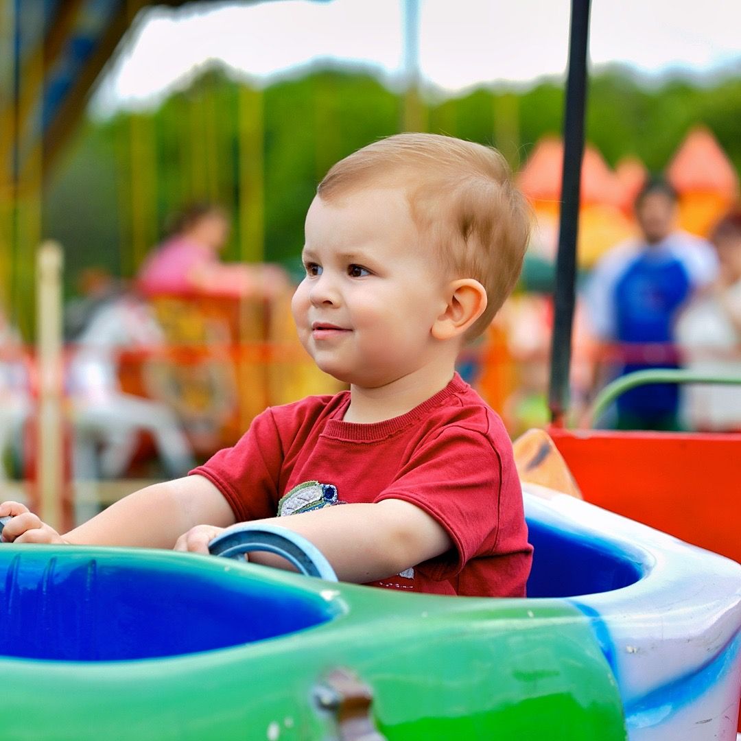 Toddler rides in a colorful amusement park car