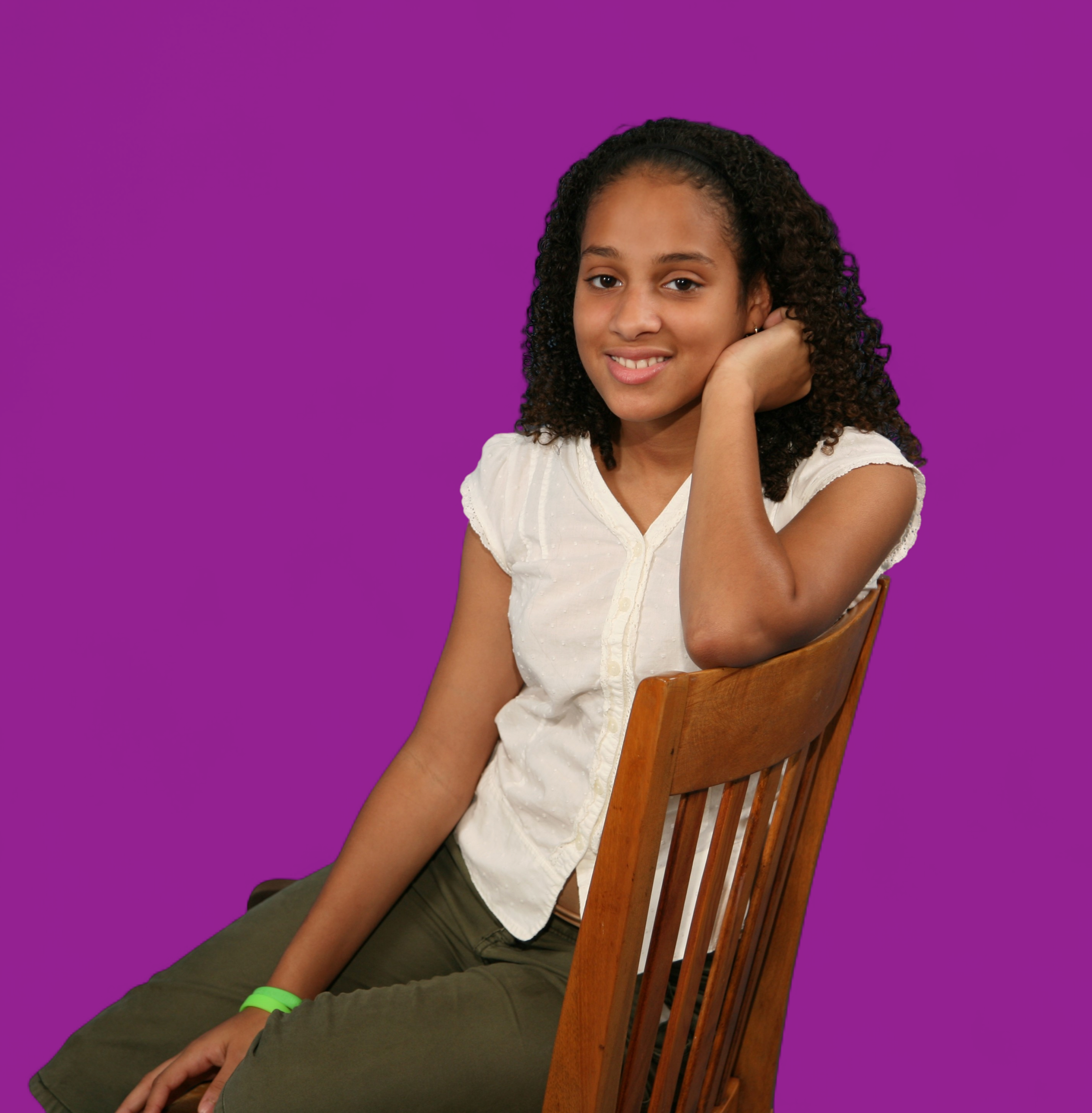 Young woman seated backward on a wooden chair, smiling
