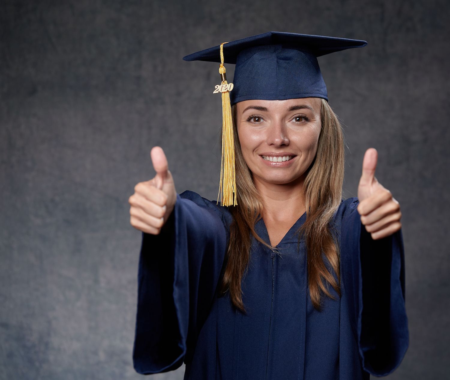 Graduate wearing a 2020 mortarboard gives two thumbs up
