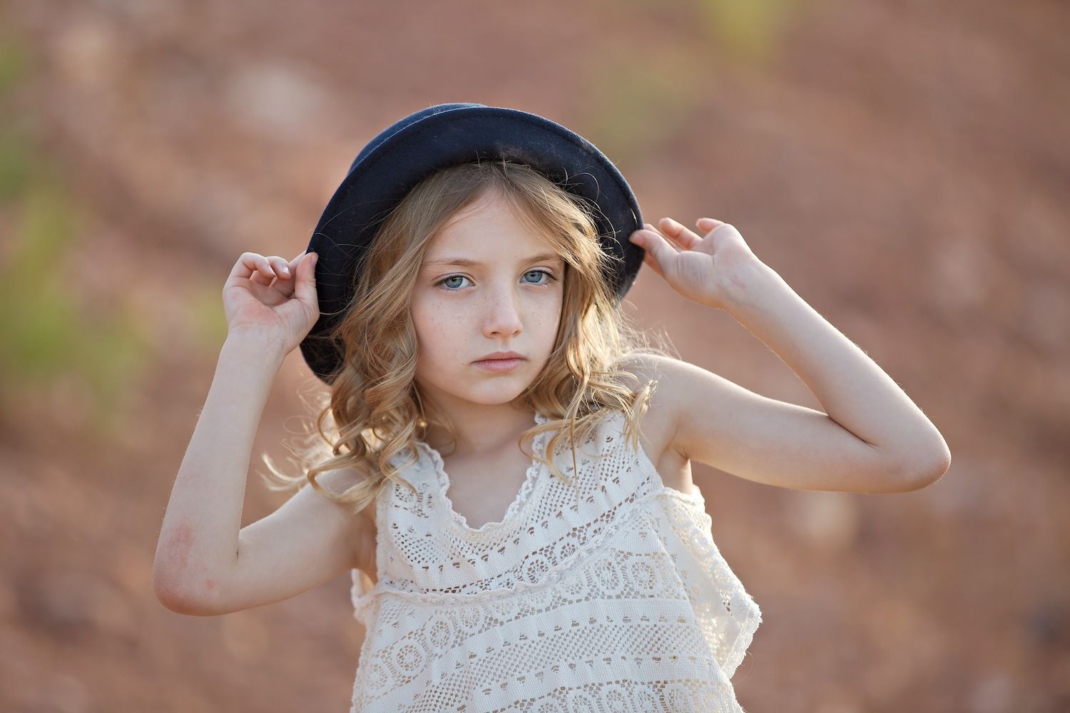 Girl in a lace top adjusts her black hat
