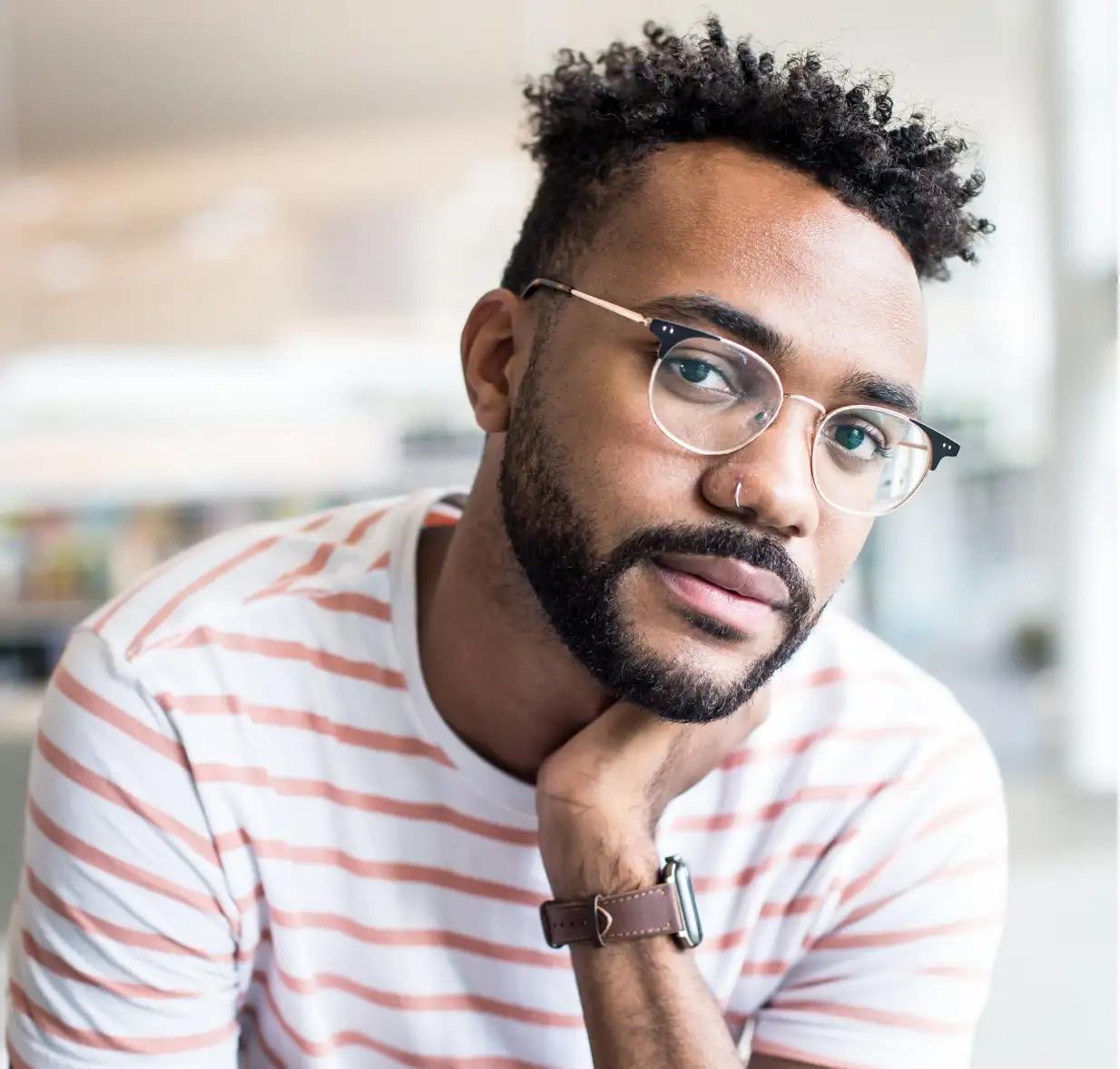 Man wearing glasses rests his chin on his hand