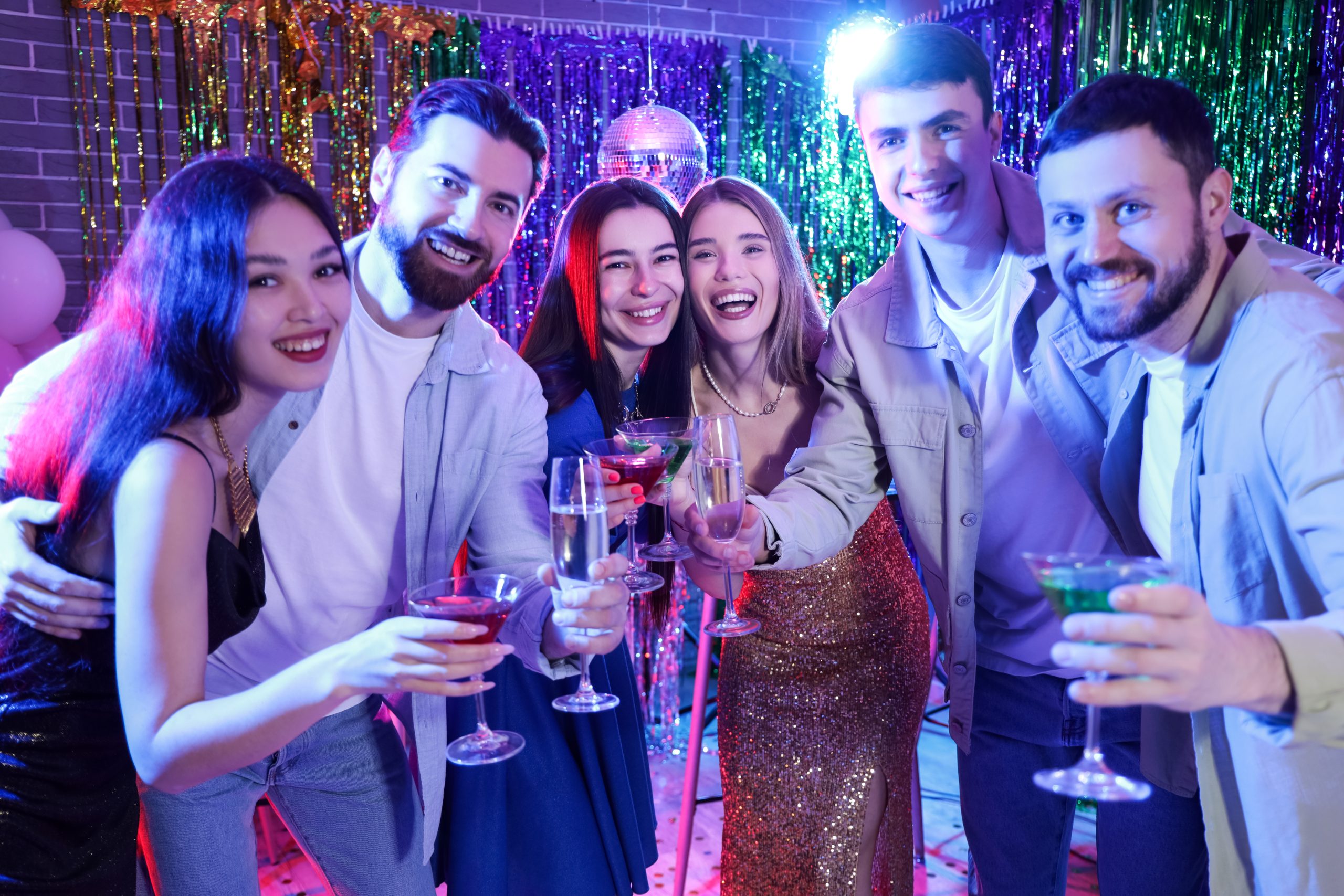 Six friends raise cocktails together at a party