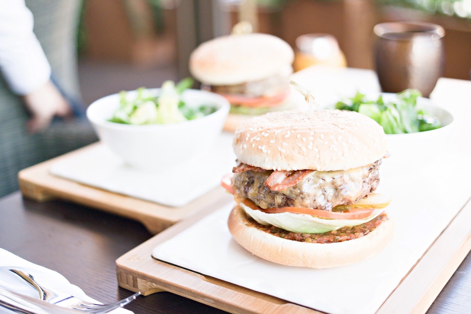 Cheeseburger with lettuce and tomato served alongside a green salad
