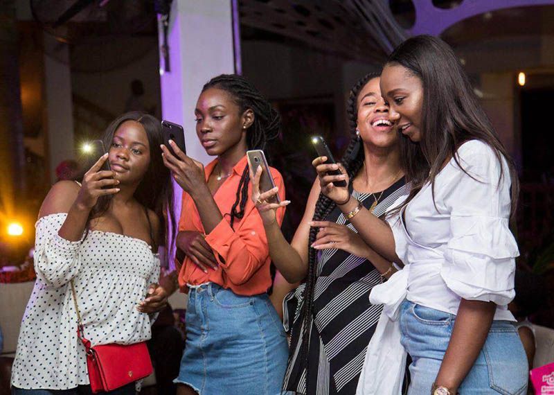 Four women look at their phones together at an event