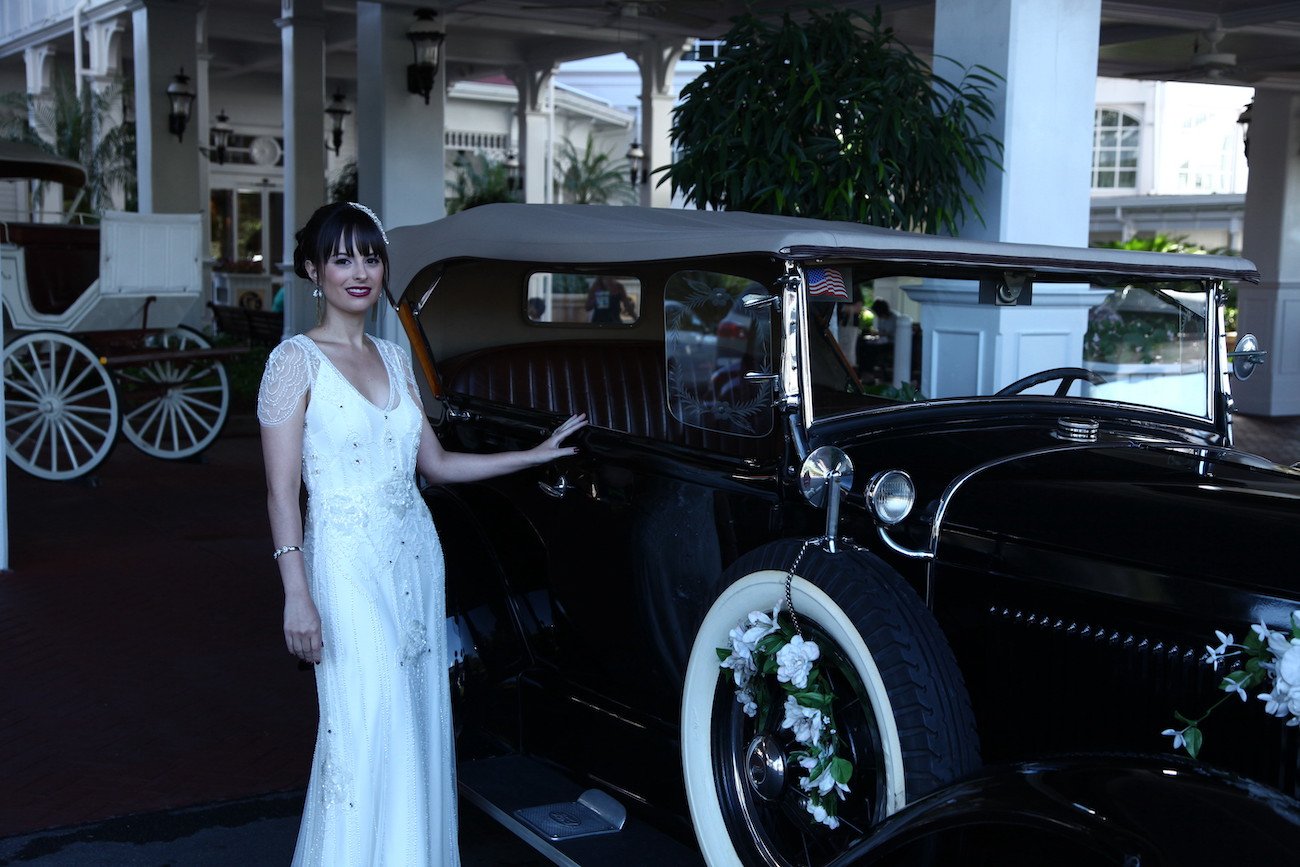 Bride stands beside a flower-decorated vintage car
