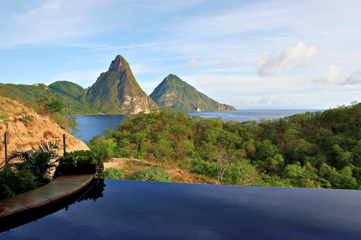 Infinity pool overlooking forested volcanic peaks and the sea