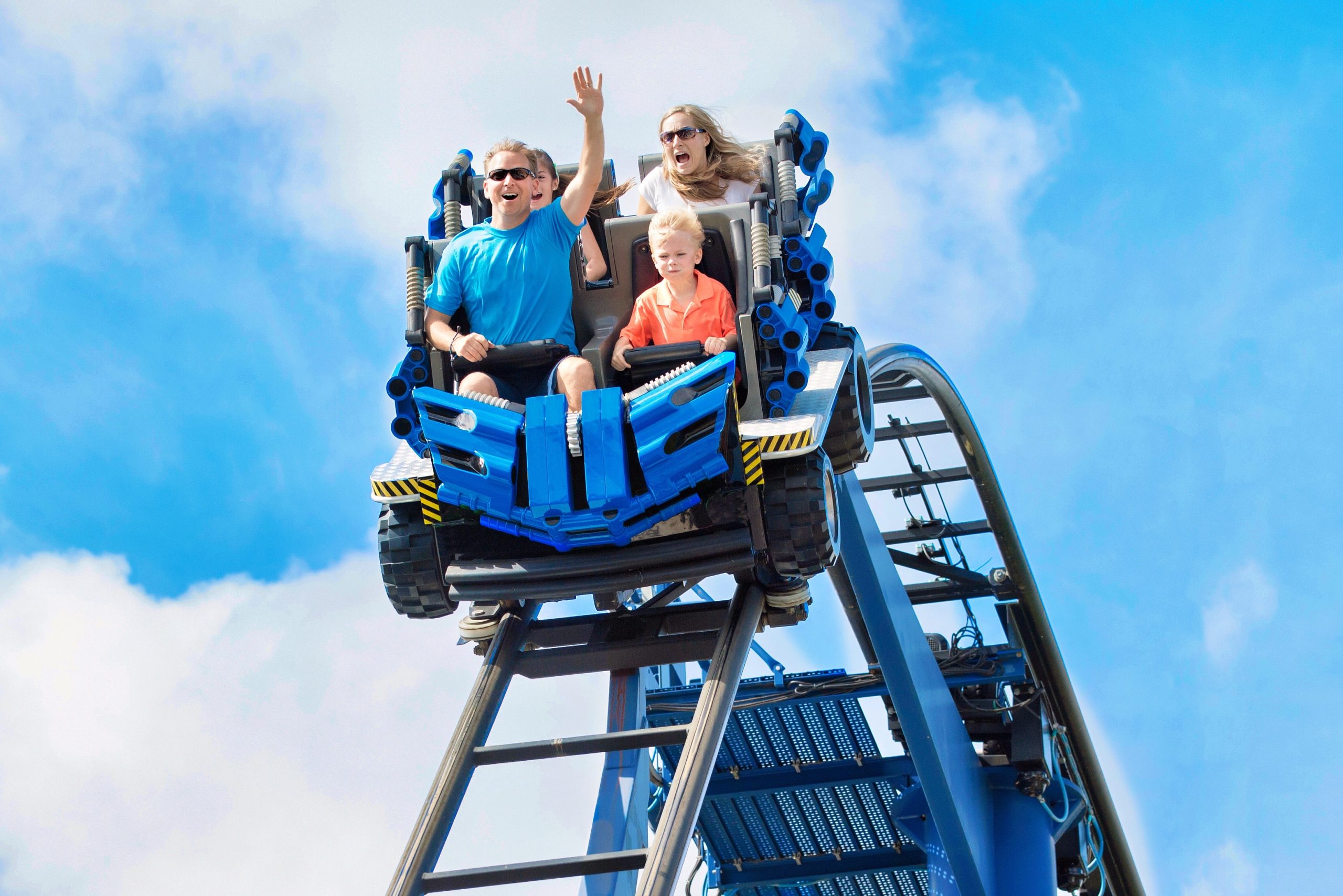 Family rides a roller coaster over the crest of a hill