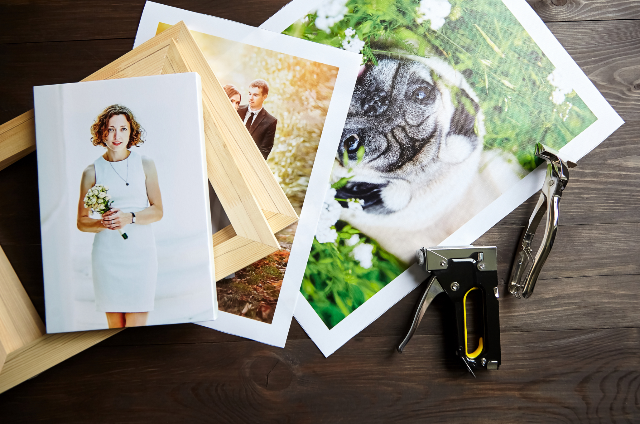 Printed photographs, wooden frames, staple guns and pliers on a table