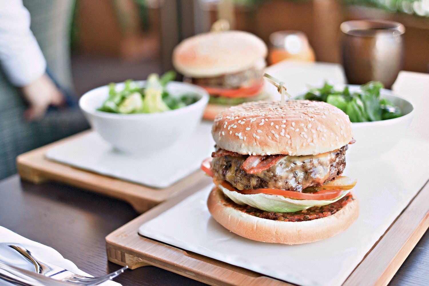 Cheeseburger with lettuce and tomato served alongside a green salad