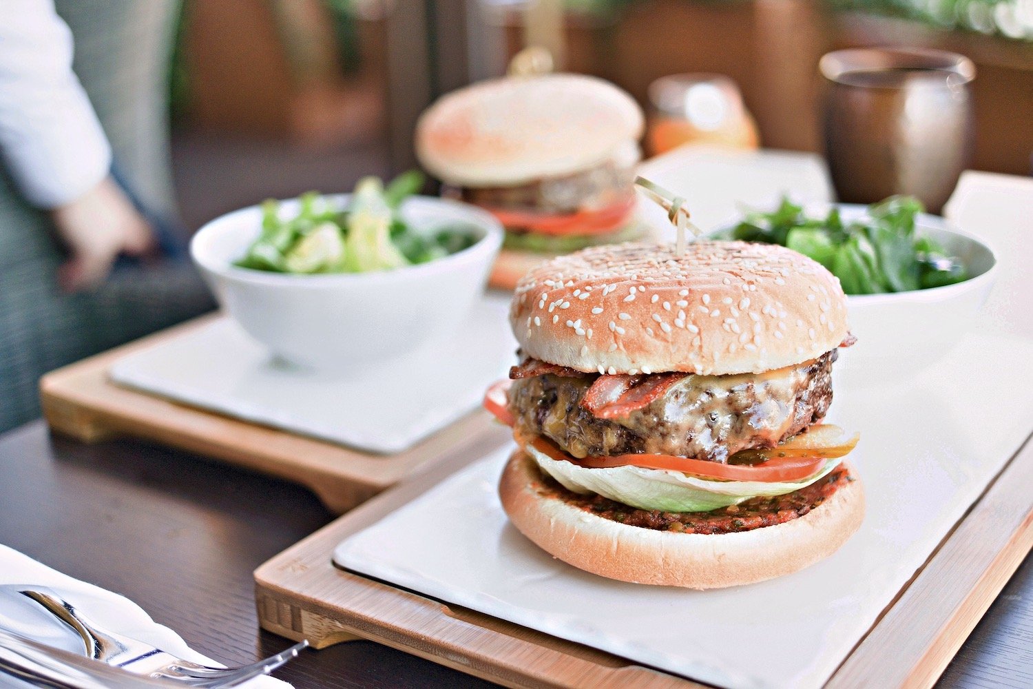 Cheeseburger with lettuce and tomato served alongside a green salad