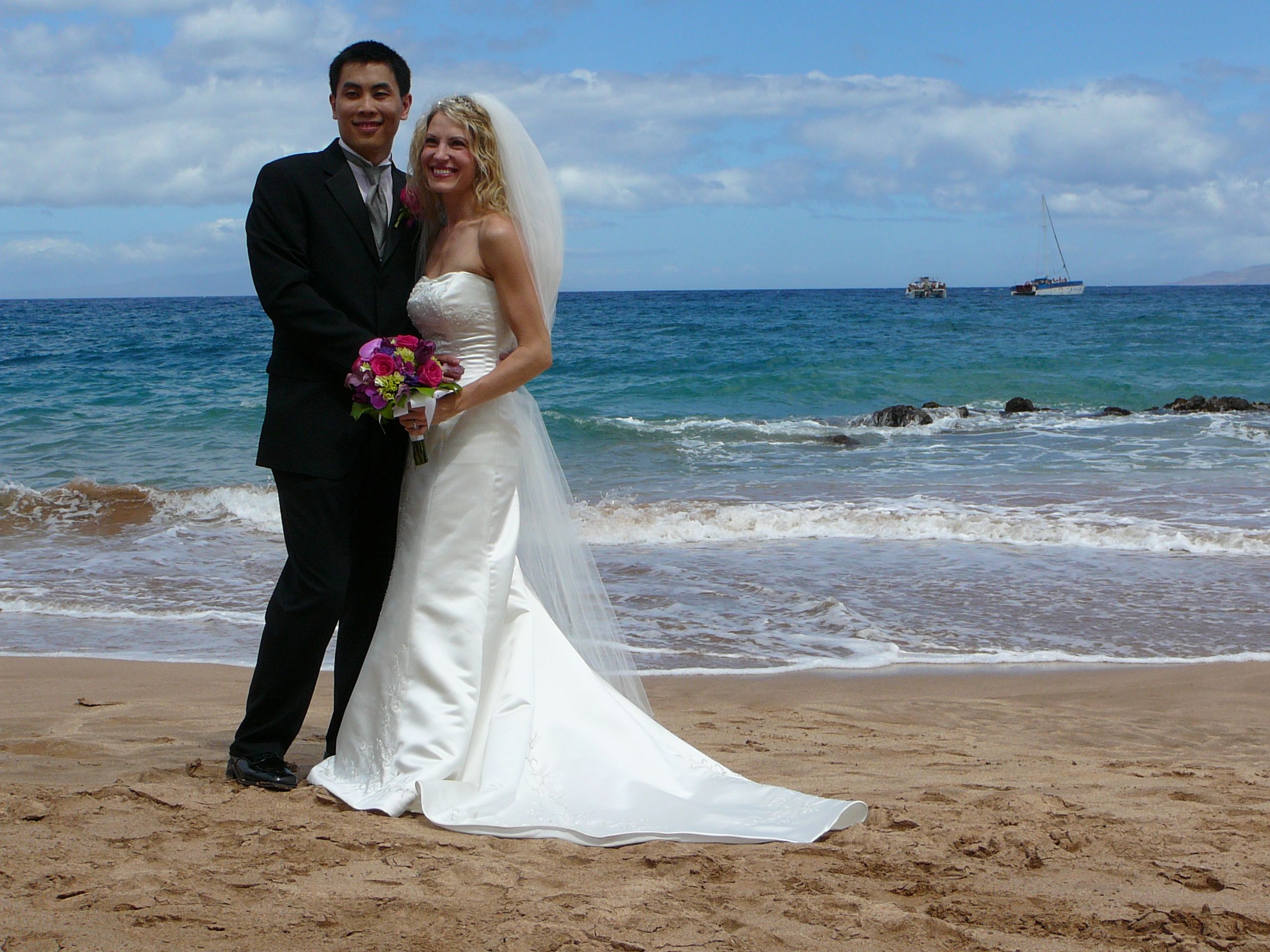 Bride and groom pose together on a beach