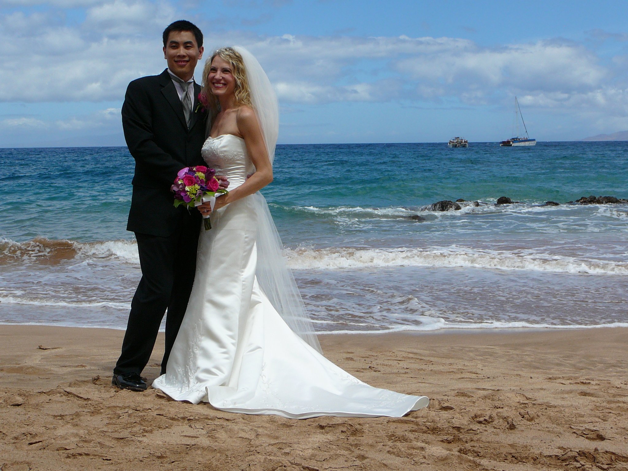 Bride and groom pose together on a beach