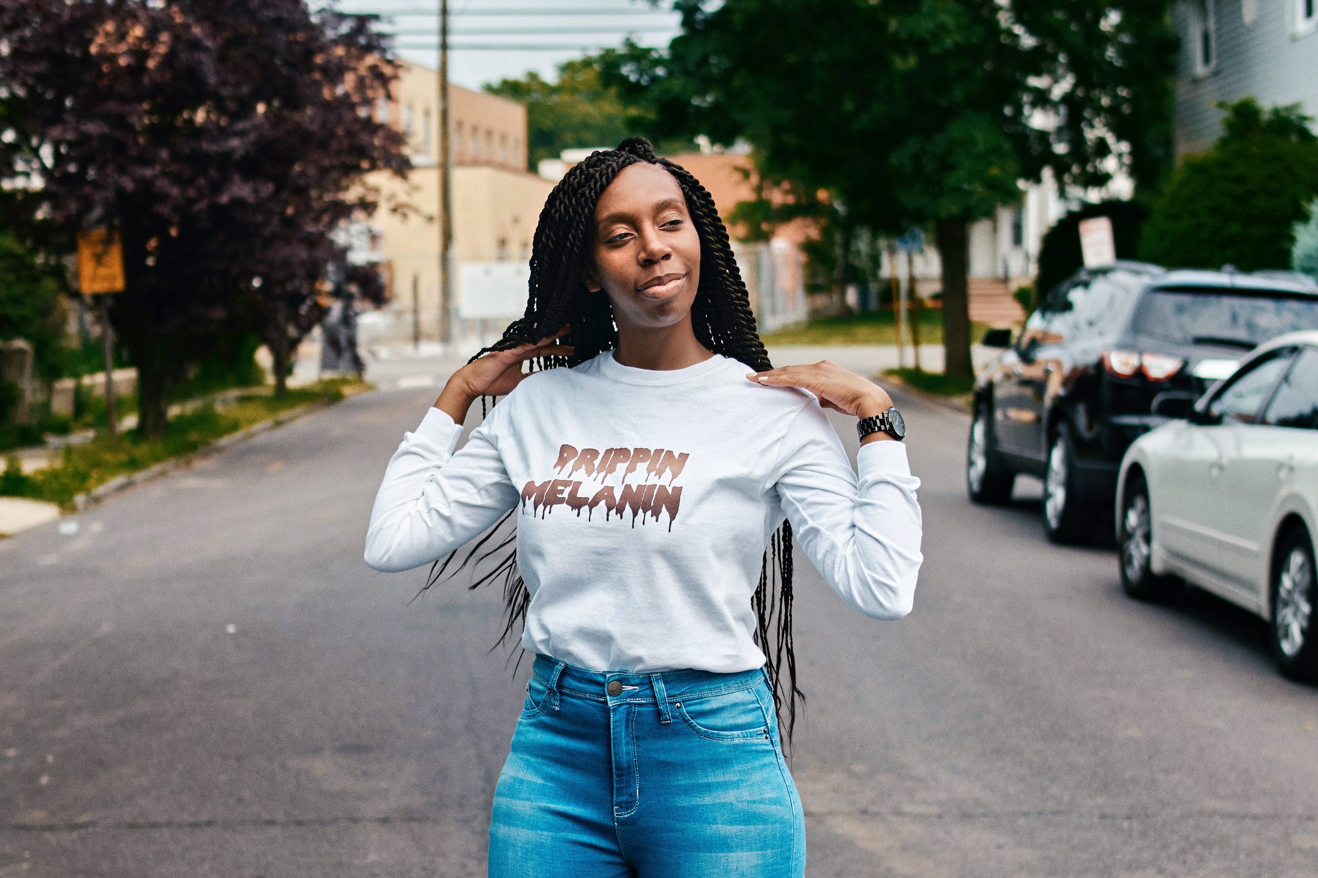 Woman standing in a street wearing a “Drippin melanin” shirt