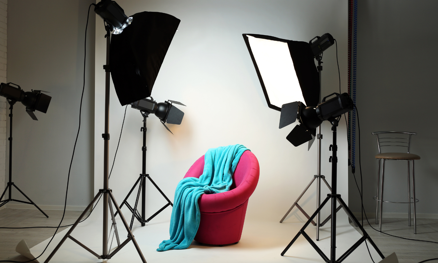 Studio lights surround an armchair draped with a blanket