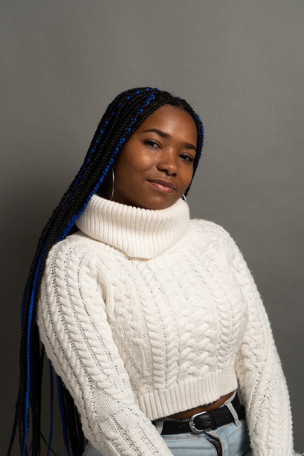 Woman with long braids wearing a white cable-knit turtleneck sweater