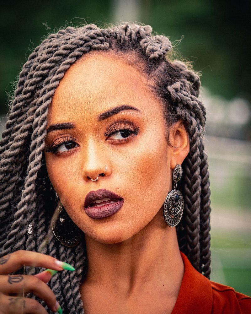 Woman with long twists, nose rings, and dangling earrings